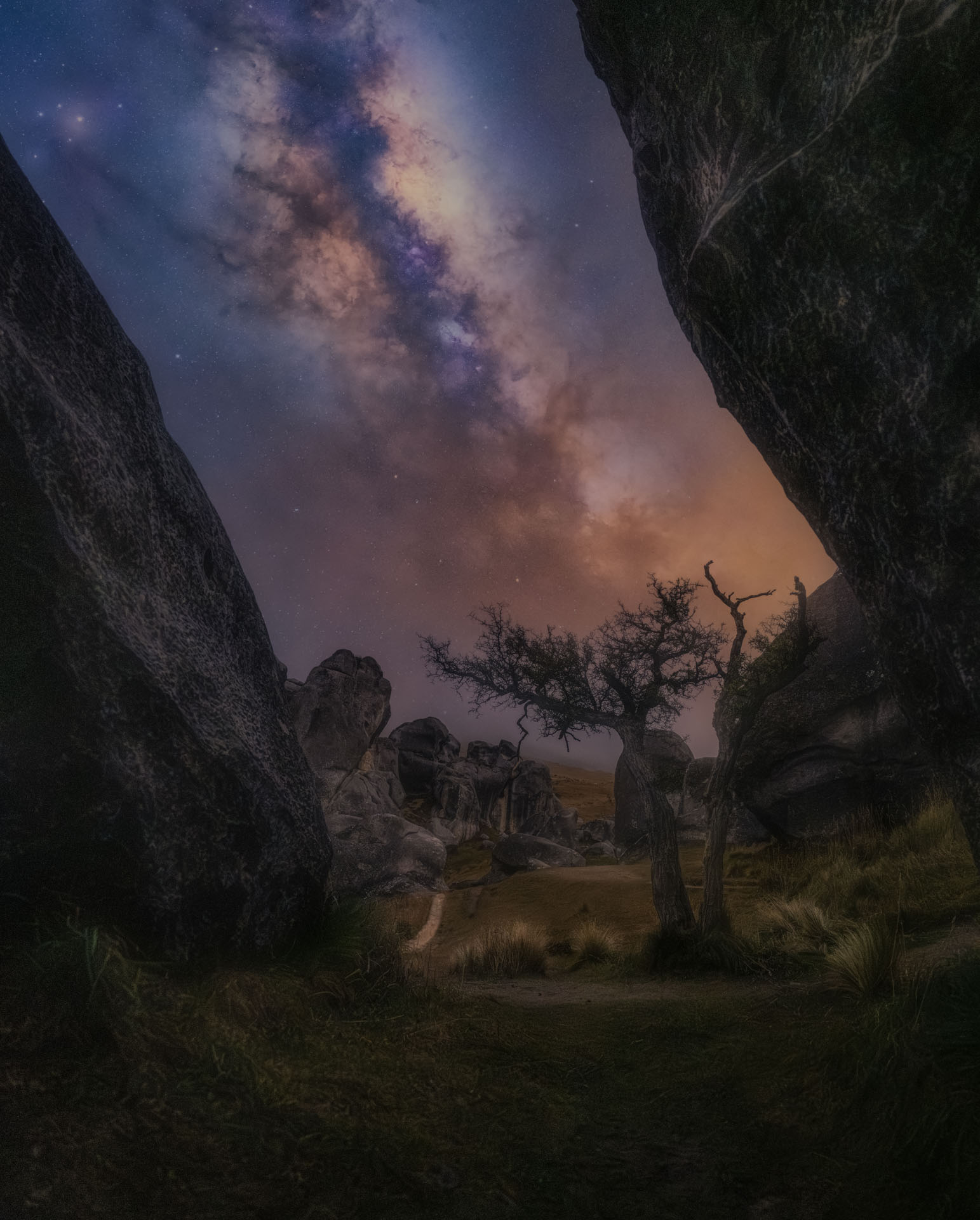 Milky Way framed between two rock formations at Castle Hill, pointing toward a lone tree