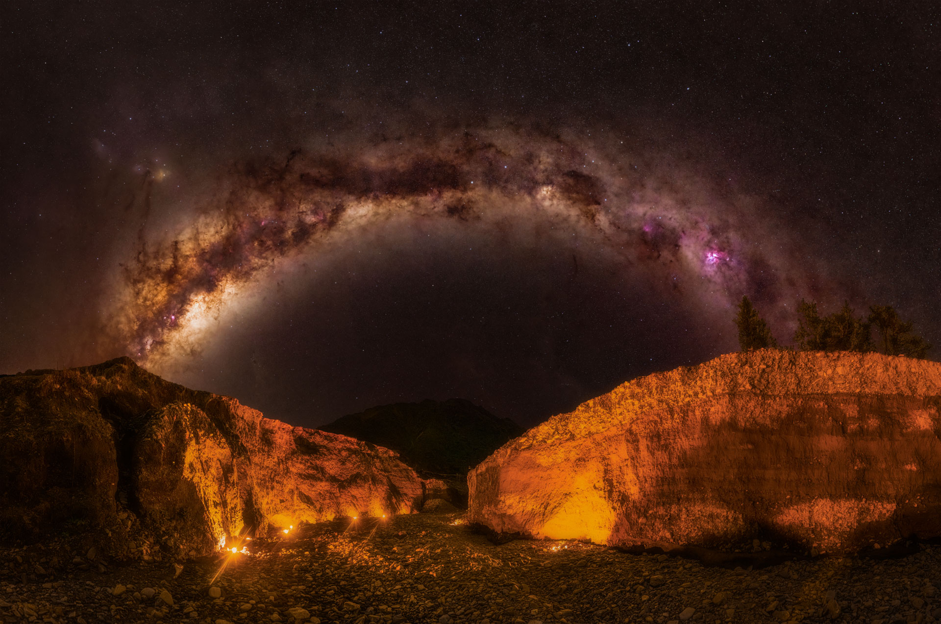 Milky Way arching over a dry ravine lit with tealight candles at Cowboys Paradise, Milltown near Lake Kaniere
