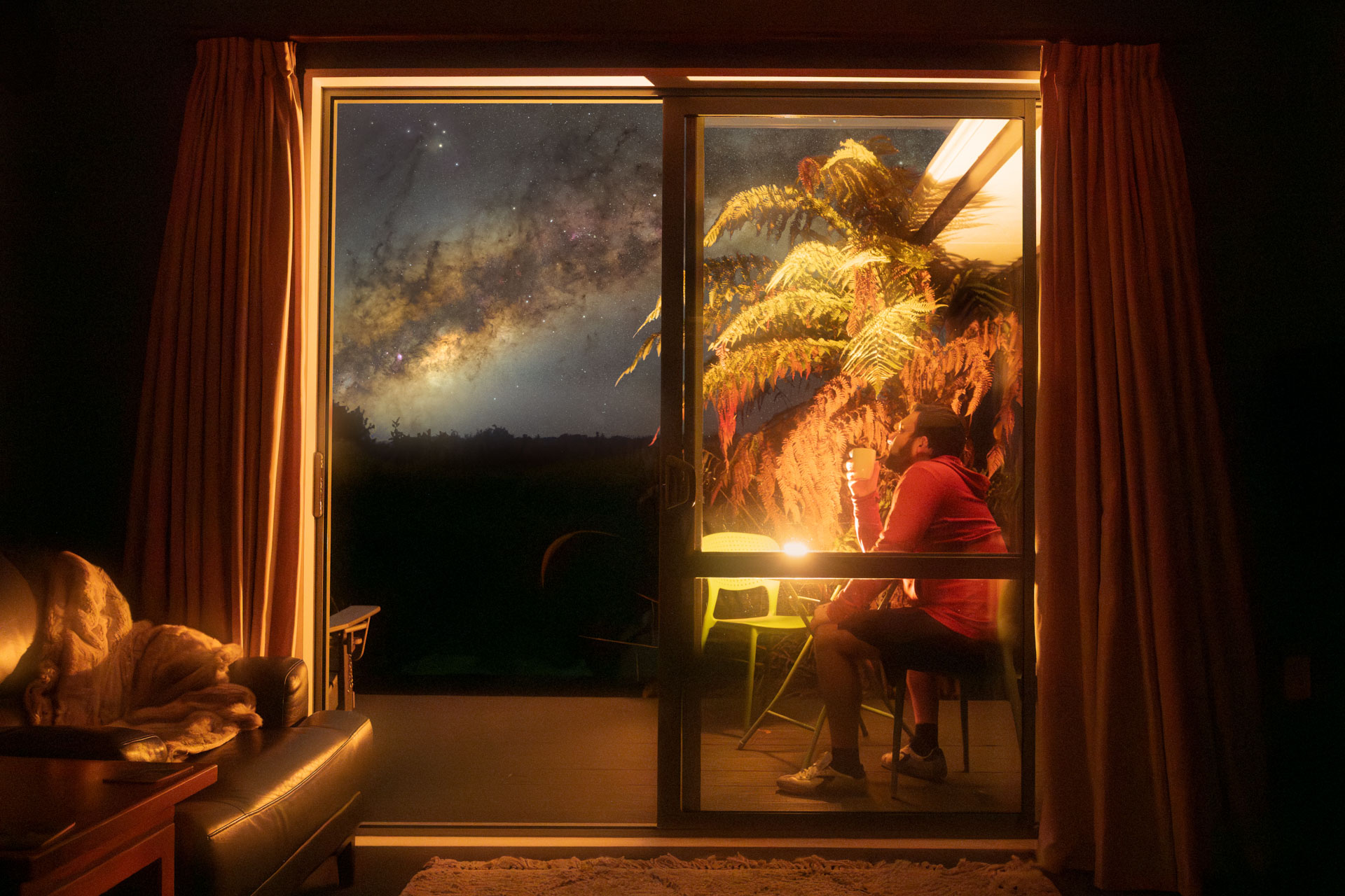 Milky Way seen through a candlelit ranch slider window at Goldfield Suites